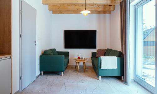 a living room with two chairs and a flat screen tv at Chata ŠENKÁRKA Zuberec in Zuberec