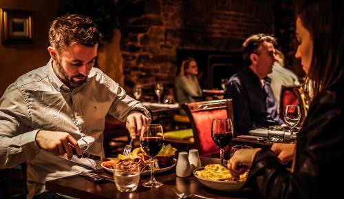 a man sitting at a table with a plate of food at Denvir's of Downpatrick in Downpatrick