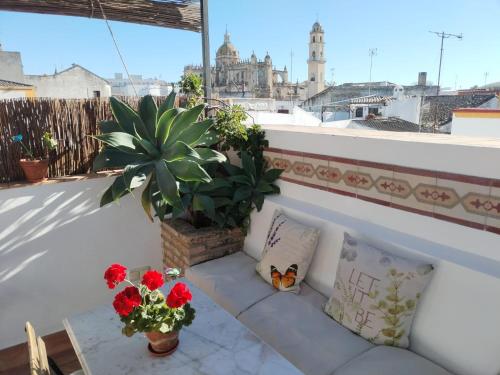 La Gitanilla Alojamiento & Encanto Jerez في خيريز دي لا فرونتيرا: أريكة على شرفة مع النباتات والورود