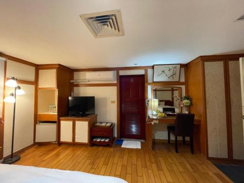 a room with a bed and a desk with a computer at River Hotel in Chiayi City