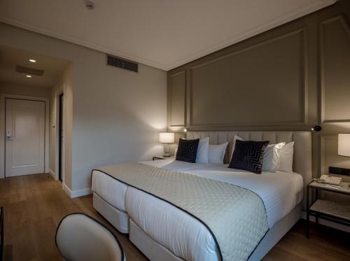 a bedroom with a large white bed and a chair at Silken Ciudad de Vitoria in Vitoria-Gasteiz