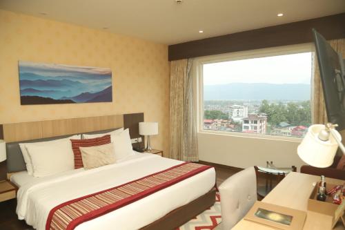 a hotel room with a bed and a large window at Vivanta Chitwan Bharatpur in Bharatpur