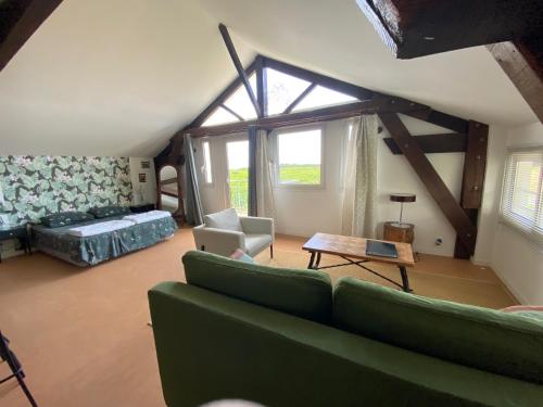 sala de estar con sofá verde y ventana en Gites le Mathelin, en Lamothe-Montravel