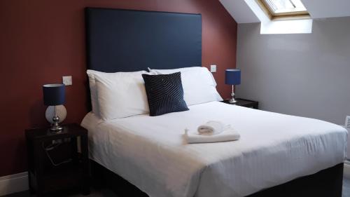 a bedroom with a large white bed with two lamps at Denvir's of Downpatrick in Downpatrick