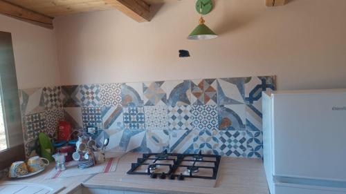 a kitchen with a stove and a tile wall at Lovely Country House in Trappeto