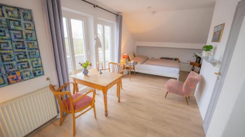 een woonkamer met een tafel en stoelen en een slaapkamer bij Schillhörn - Urlaub mit Wasserblick in Neuharlingersiel