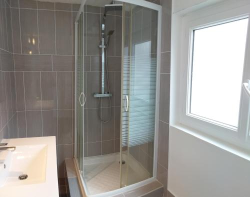 une douche avec une porte vitrée à côté d'un lavabo dans l'établissement Appartement douillet eaux bonnes/vallée d’ossau, à Eaux-Bonnes