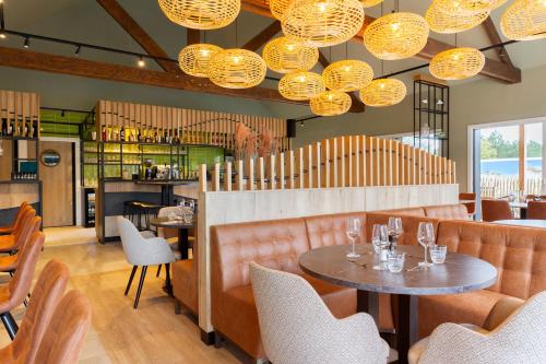 een restaurant met een tafel, stoelen en verlichting bij Dormio Resort Berck-sur-Mer in Berck-sur-Mer