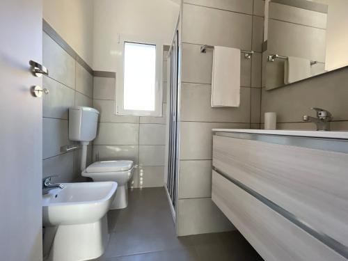 a white bathroom with a sink and a toilet at Green Village in Marina di Camerota