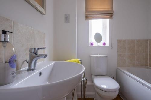 een witte badkamer met een wastafel en een toilet bij Alice Cottage in Camber