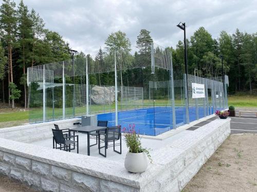 a tennis court with a table and chairs next to a pool at Holiday home Mellösa IV in Mellösa