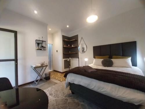 Lydiana Guesthouse في بريتوريا: غرفة نوم بسرير كبير وطاولة