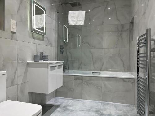 ein Badezimmer mit einer Badewanne, einem WC und einem Waschbecken in der Unterkunft Watford Central Apartments - Modern, spacious and bright 1 bed apartments in Watford