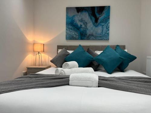 ein Schlafzimmer mit einem großen Bett mit blauen und weißen Kissen in der Unterkunft Watford Central Apartments - Modern, spacious and bright 1 bed apartments in Watford