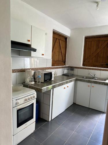 uma cozinha com electrodomésticos brancos e armários de madeira em AZARIA em Le Gosier