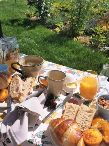 un tavolo con pane, succo d'arancia e bicchieri di succo d'arancia di Au Jardin des Deux Roches a Prissé