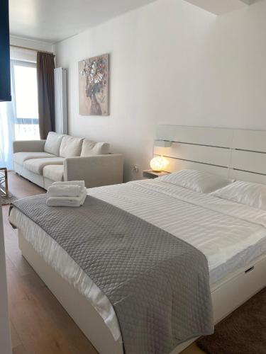 a white bedroom with a large bed and a couch at Queen's Studio Deluxe Mamaia Nord in Mamaia Nord