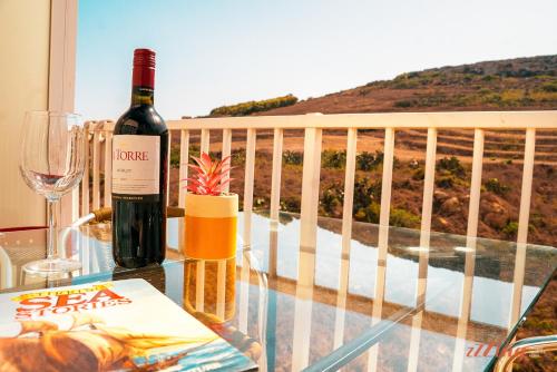 a bottle of wine sitting on a glass table on a balcony at A seaside holiday home with country views in Żebbuġ