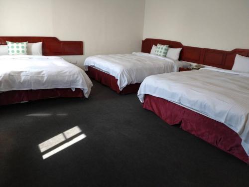 two beds in a hotel room with the sun shining on them at River Hotel in Chiayi City