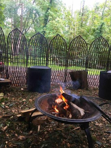 a fire pit in a yard with a fence at little vintage caravan with cosy log burner in Canterbury