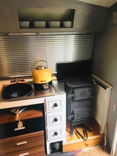 a kitchen with a stove with a pot on it at little vintage caravan with cosy log burner in Canterbury