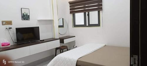 Habitación blanca con cama y TV en HOMESTAY -NHÀ MẸ KHANG en Cu Chi