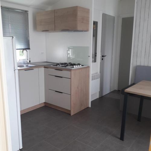 a kitchen with white cabinets and a stove top oven at Camping de Brouël in Ambon