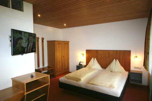 Schlafzimmer mit einem Bett und einem Kopfteil aus Holz in der Unterkunft Hotel-Pension Stallinger in Weyregg