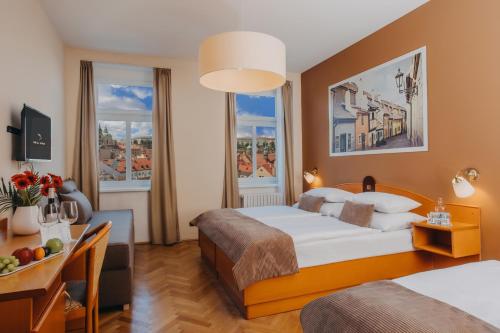 a hotel room with a bed and a desk and two windows at Hotel Merkur - Czech Leading Hotels in Prague