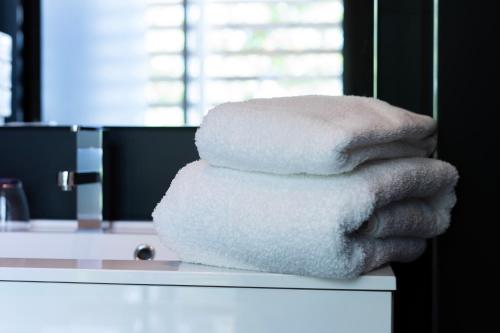 sterta ręczników na blacie w łazience w obiekcie Chambre La Fleur w mieście Néac