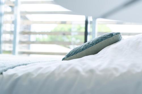białe łóżko z poduszką w obiekcie Chambre La Fleur w mieście Néac