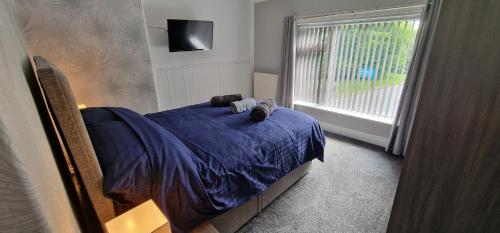 sypialnia z łóżkiem z niebieską pościelą i oknem w obiekcie Cosy, spacious and comfortable family home. w mieście Kirkburton