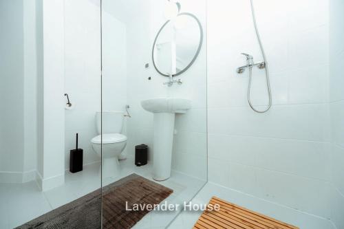 a white bathroom with a shower and a toilet at Lavender House in Osieki