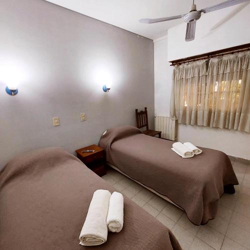 2 Betten in einem Hotelzimmer mit Handtüchern darauf in der Unterkunft Posada del Angel in Neuquén