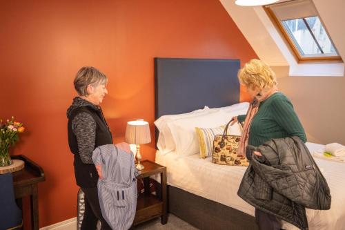 two women standing in a bedroom with a bed at Denvir's of Downpatrick in Downpatrick