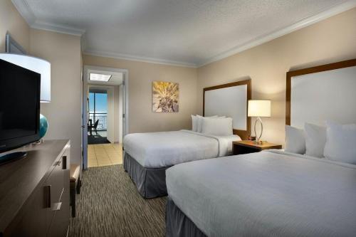 a hotel room with two beds and a flat screen tv at Modern 1BR Oceanfront Condo at Coral Beach Resort in Myrtle Beach