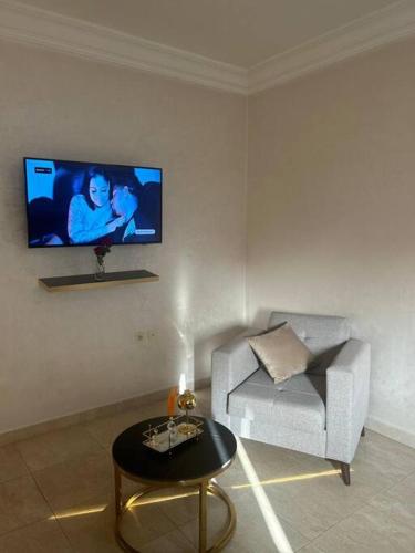 uma sala de estar com um sofá e uma televisão na parede em Appartement jnane aourad em Marrakech