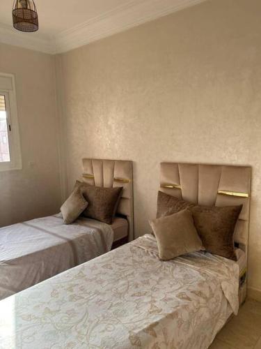 um quarto com duas camas com almofadas em Appartement jnane aourad em Marrakech