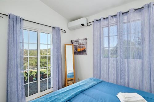 a bedroom with a blue bed and a large window at Laranjeira by Vintage Travel in Tavira