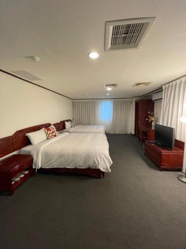 a bedroom with a large bed and a television at River Hotel in Chiayi City