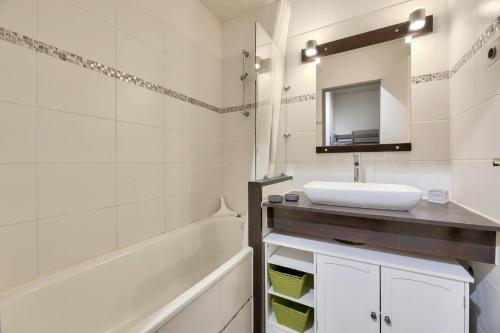 uma casa de banho com um lavatório, uma banheira e um espelho. em Residence Saint-Raphael Valescure - maeva Home em Saint-Raphaël