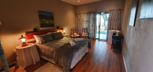 a bedroom with a large bed and a sliding glass door at Berlouri Guest House in Hekpoort