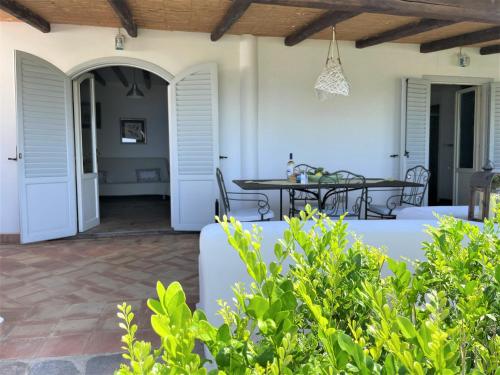 un patio con puertas blancas, mesa y sillas en Casa Surya - Sea view terrace, Isola Salina, en Malfa