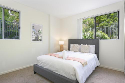a white bedroom with a bed and two windows at Castle HIll Sweet Modern 3BR Apt with 2 Parking in Castle Hill