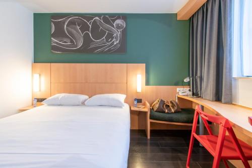 a hotel room with a bed and a desk at ibis De Panne in De Panne
