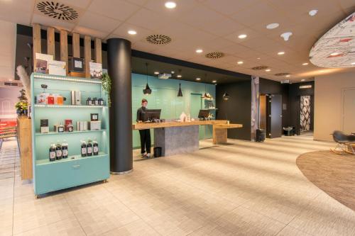 a man is standing at a counter in a lobby at ibis De Panne in De Panne