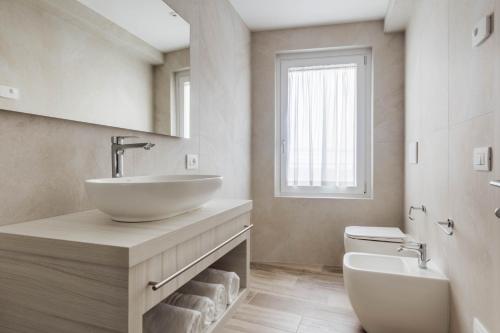 a white bathroom with a sink and a toilet at Hotel Giardinetto in Garda