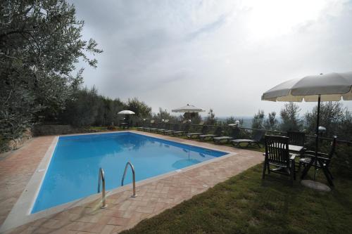 - une piscine avec une table, des chaises et un parasol dans l'établissement Gli Oleandri, à Castelfiorentino