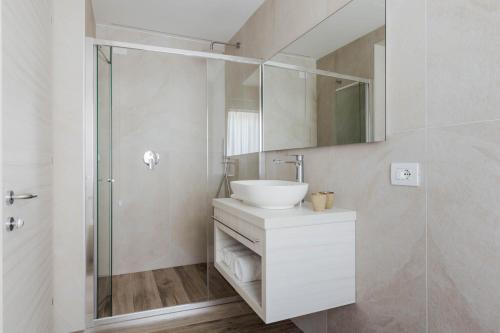 a white bathroom with a sink and a shower at Hotel Giardinetto in Garda