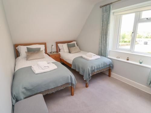 two twin beds in a room with a window at Alnside Cottage in Alnmouth
